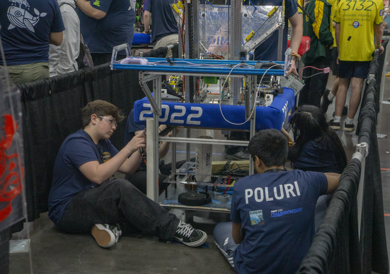 Team members changing the robot's swerve modules while in line for the practice field.